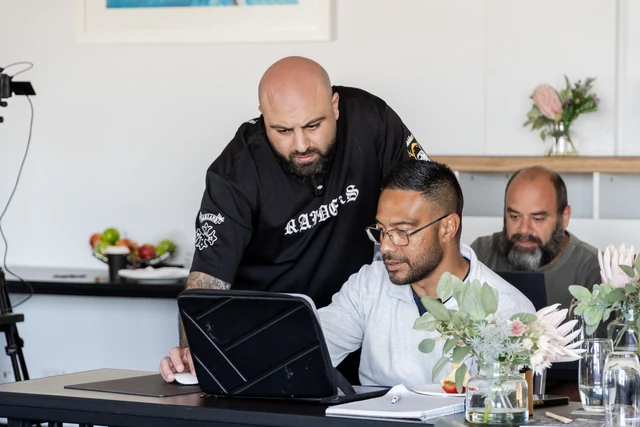 A trainer helping a participant at their laptop during a LaunchHub workshop